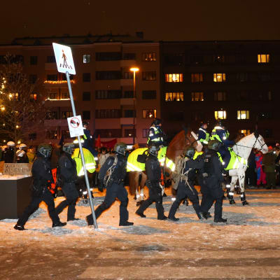 Mellakkavarusteiset poliisit ja ratsupoliisit tyhjentävät mielenosoittajia Töölöntorilta.