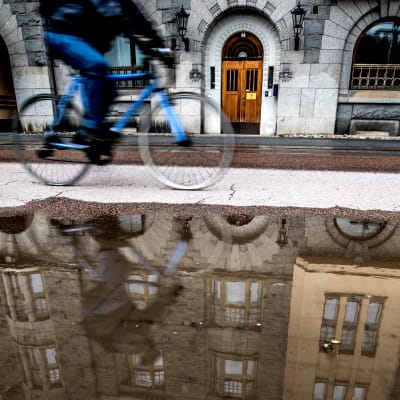 En cyklist cyklar invid en stor vattenpöl i Åbo.