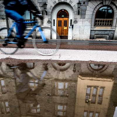 En cyklist cyklar invid en stor vattenpöl i Åbo.