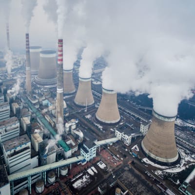 Flera fabriksbyggnader, skorstenar och nedkylningstorn vid kinesiskt kolkraftverk fotograferade uppifrån.  