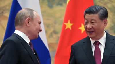 Rysslands Putin och Kinas Xi diskuterar. I bakgrunden ser man ländernas flaggor.