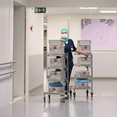 Leikkaussalihoitaja Tiina Kirssi työntää tavarakärryjä Mikkelin keskussairaalan käytävällä.