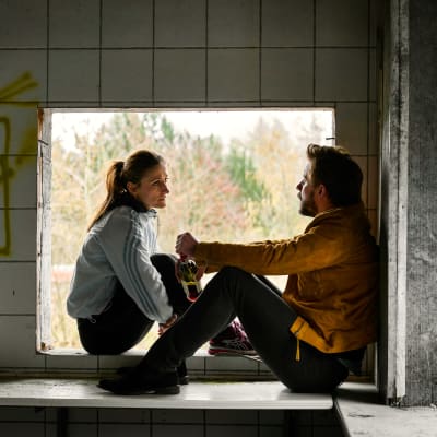 Martin & Anna / Anders Juul & Marijana Jancovic sitter i fönster i övergivet hus.