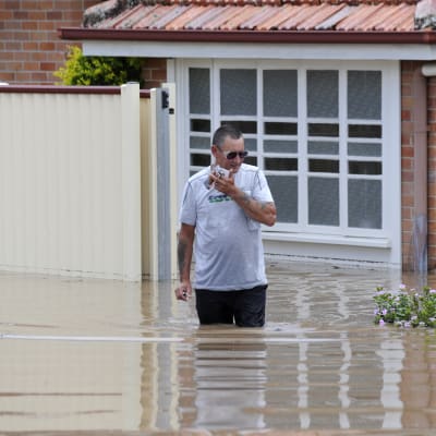 En man utanför sitt översvämmade hus i Bundaberg