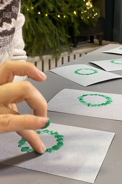 Fingerfärgstryckning med grön färg på grå kartong