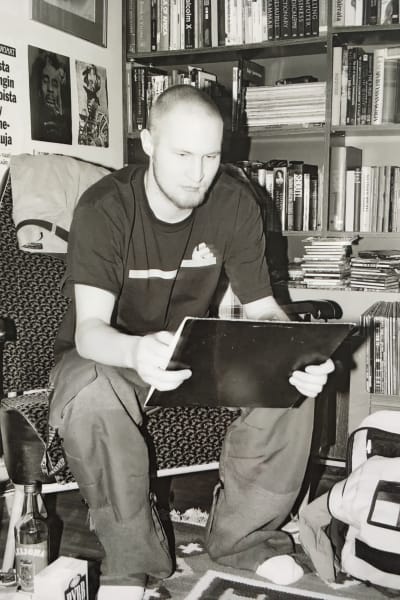 Svartvit bild på Palface som ung sittande på stol i arbetsrum med en tavla eller häfte i handen som han studerar.