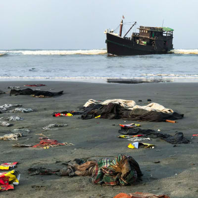En del av de räddade rohingyernas ägodelar låg kvar på stranden nära Teknaf på torsdag morgon. Det är oklart om trålaren i bakdrunden är den båt som de drivit omkring på i nästan två månader. 