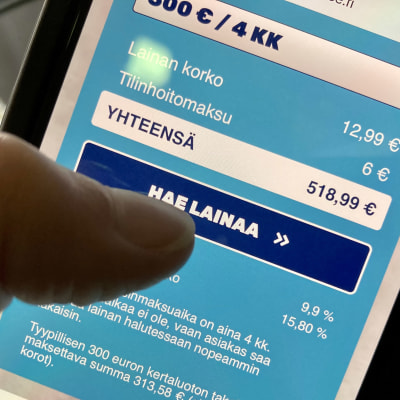 Kännykässä näkyy Blue Financen nettisivut, lähikuvassa peukalo on painamassa "hae lainaa" näppäintä.