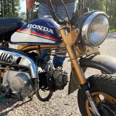 Honda Monkey (Z50J) -merkkinen mopedi, taustalla näkyy farkkuasuisen miehen jalat.
