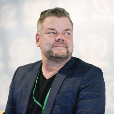 Jari Sillanpää med blå kostym och skägg. 