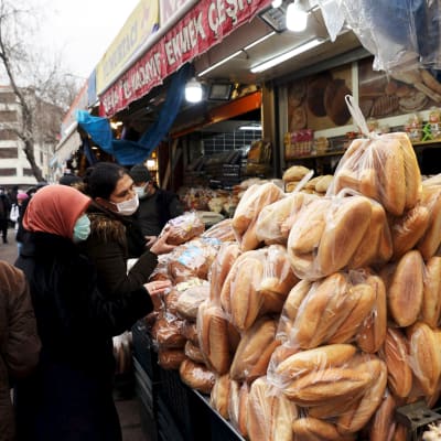 Asiakkaat ostavat leipää ruokatorilla.
