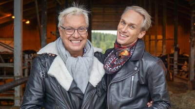 Christoffer och Lars-Åke står i ett fähus och ler mot kameran.