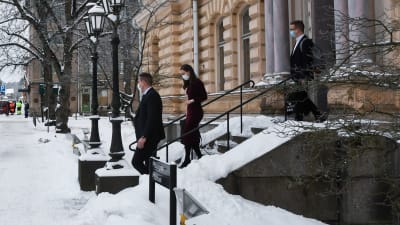 Tre personer går nerför trappan utanför Borgå stadshus. Det är Sanna Marin samt hennes säkerhetsvakt och assistent.