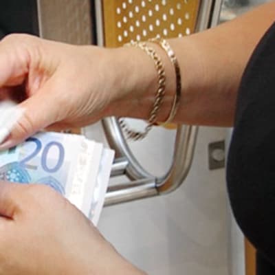 Nainen laskee rahojaan pankkiautomaatilla.