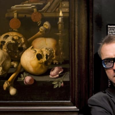 Damien Hirst poseeraa pääkallomaalauksen vieressä, joka sijaitsee Amsterdamin Rijksmuseumissa.