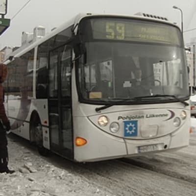 Bussi numero 59 Helsingissä Pasilan asemalla talvella. Matkustajia nousee bussiin.