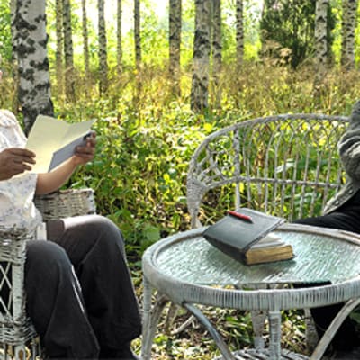 Leila (Karina Hazard) lukee kirjettä pappi Jaakobille (Heikki Nousiainen) puutarhapöydän ääressä koivikossa.