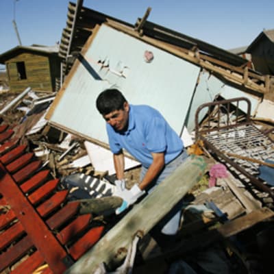 Mies etsii tavaroita romahtaneen talon raunioissa Chilessä.