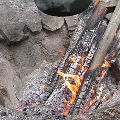 Kivillä vuoratussa rosvopaistihaudassa poltetaan nuotiota
