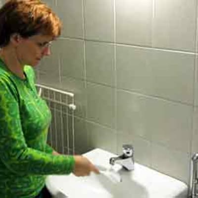 Kuvassa nainen puhdistaa käsienpesuallasta