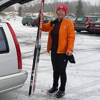 Hiihtäjä laittaa suksia autoon Paloheinässä.
