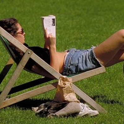 nainen lukee kirjaa aurinkotuolissa