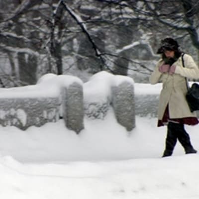 Nainen kävelee lumisessa Kaisaniemessä Helsingissä.