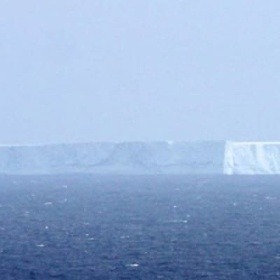 Jättiläismäinen jäävuori ajelehtii avomerellä.