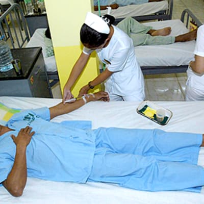 Filippiiniläinen sairaanhoitaja hoitaa tulitaistelussa haavoittunutta sotilasta Zamboanga Cityn sotilassairaalassa 13.8.2009.