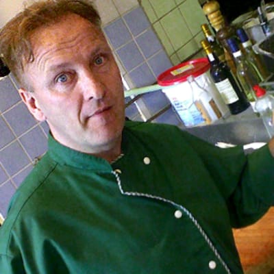 Mieskokki keittiössä lihapalojen äärellä, veitsi kädessään