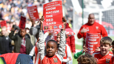 Barn håller upp Red card to racism-kort.
