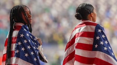Två amerikanska idrottare har USA:s flaggor runt sig på löpbanorna.