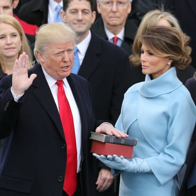 Donald Trump svär presidenteden med handen på två biblar som Melanie Trump håller.