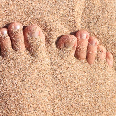 Fötter på sandstrand.