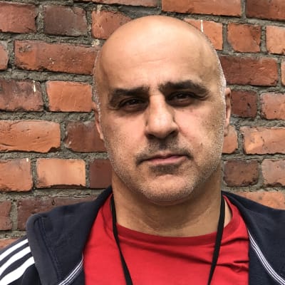 Fereidun Ahkami, som tidigare jobbat som tolk i Afghanistan, står utanför sin arbetsplats i Helsingfors.