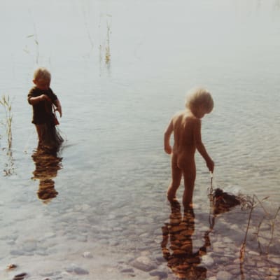 Karin Pennanen och hennes lillebror Ontrei leker med nät som ligger i blöt i sjön. Året är 1980. 