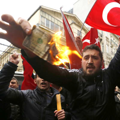 Anhängare av president Recep Tayyip Erdoğan brände upp en amerikansk dollar och skrek slagord mot Nederländerna utanför det holländska konsulatet i Istanbul den 12 mars 2017.