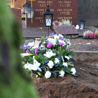 En grav med vita och lila buketter på begravningsplatsen i Borgå. Man ser att en begravning nyss har ägt rum.