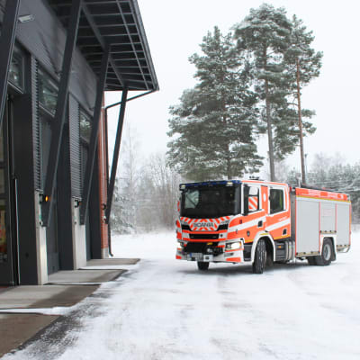 En brandbil på brandstationens gård en dag med mycket snö.