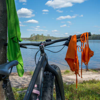 Läskipyörä kansallispuistossa järvenrannalla. Uima-asu kuivuu ohjaustangolla.
