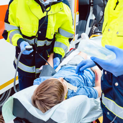 Ambulanspersonal hjälper skadad pojke