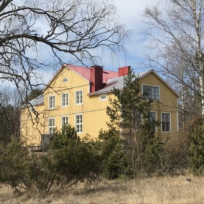 Käldinge före detta skola, en stor gul byggnad i vårgrönska.