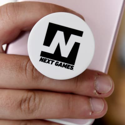Next Games -logo puhelimen pidikkeessä.