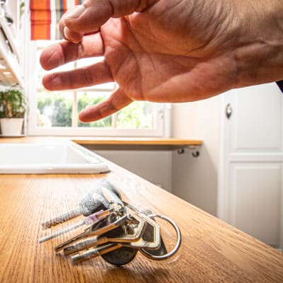 Käsi pudottaa asunnon avaimet keittiötasolle.
