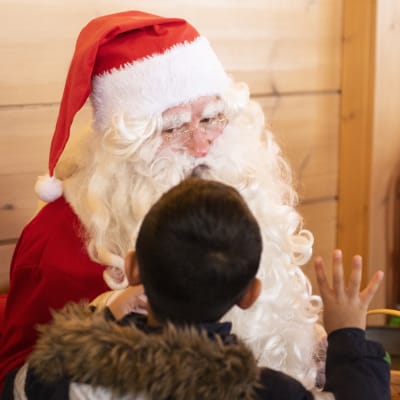Ett barn berättar sina julklappsönskemål till julgubben.