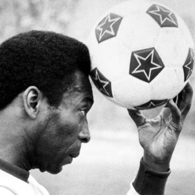 Pelé håller en fotboll mot huvudet.