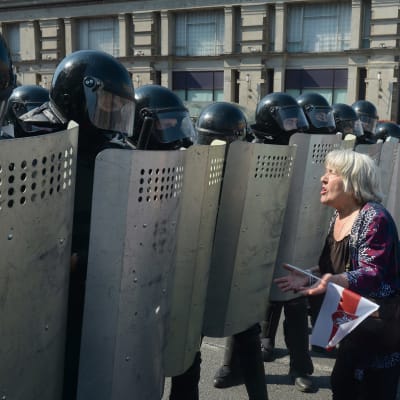 En dam talar med poliser som bevakar demonstration i Minsk 30.8.2020