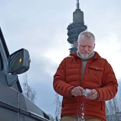 Pata Degerman kramar en snöboll i handen, framför sin terrängbil.