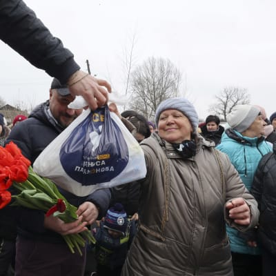 Ukrainalaiset vapaaehtoiset ojentavat kukkia paikallisille naisille kansainvälisenä naistenpäivänä kylässä lähellä Chuhuivia.