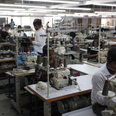 Textilarbetare syr ihop tröjor i fabrik.